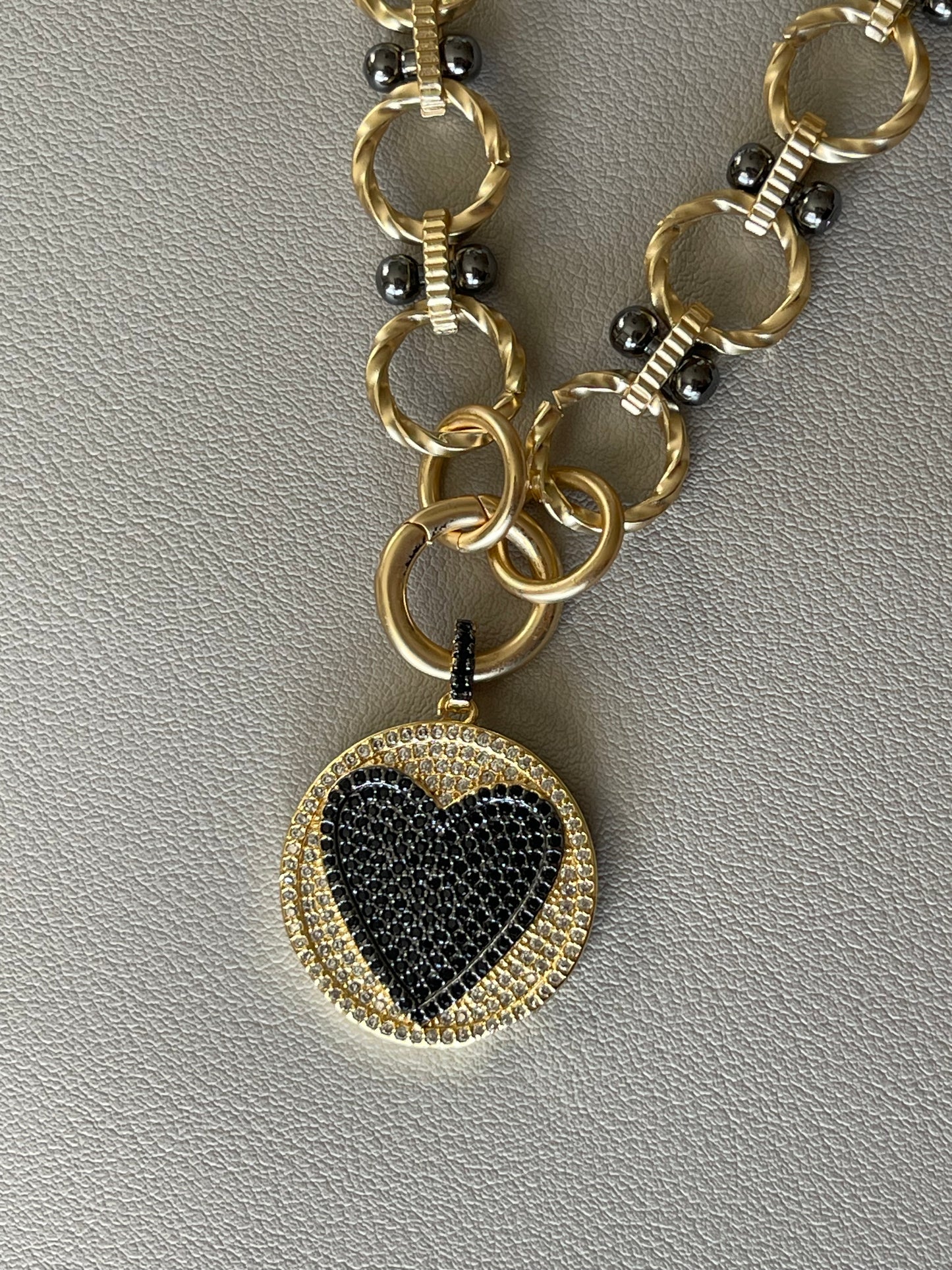 Heart On Your Sleeve Necklace: Brushed gold chain with gunmetal accents, a push gate circle clasp and pavé heart pendant