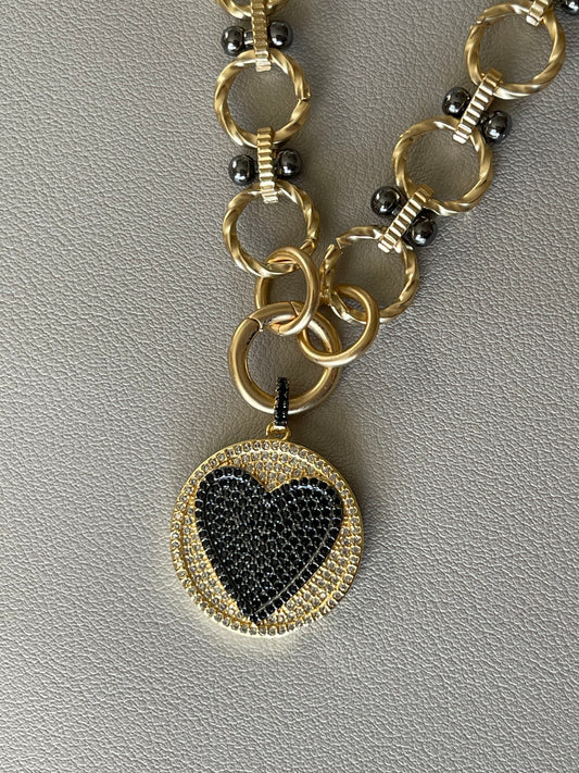 Heart On Your Sleeve Necklace: Brushed gold chain with gunmetal accents, a push gate circle clasp and pavé heart pendant