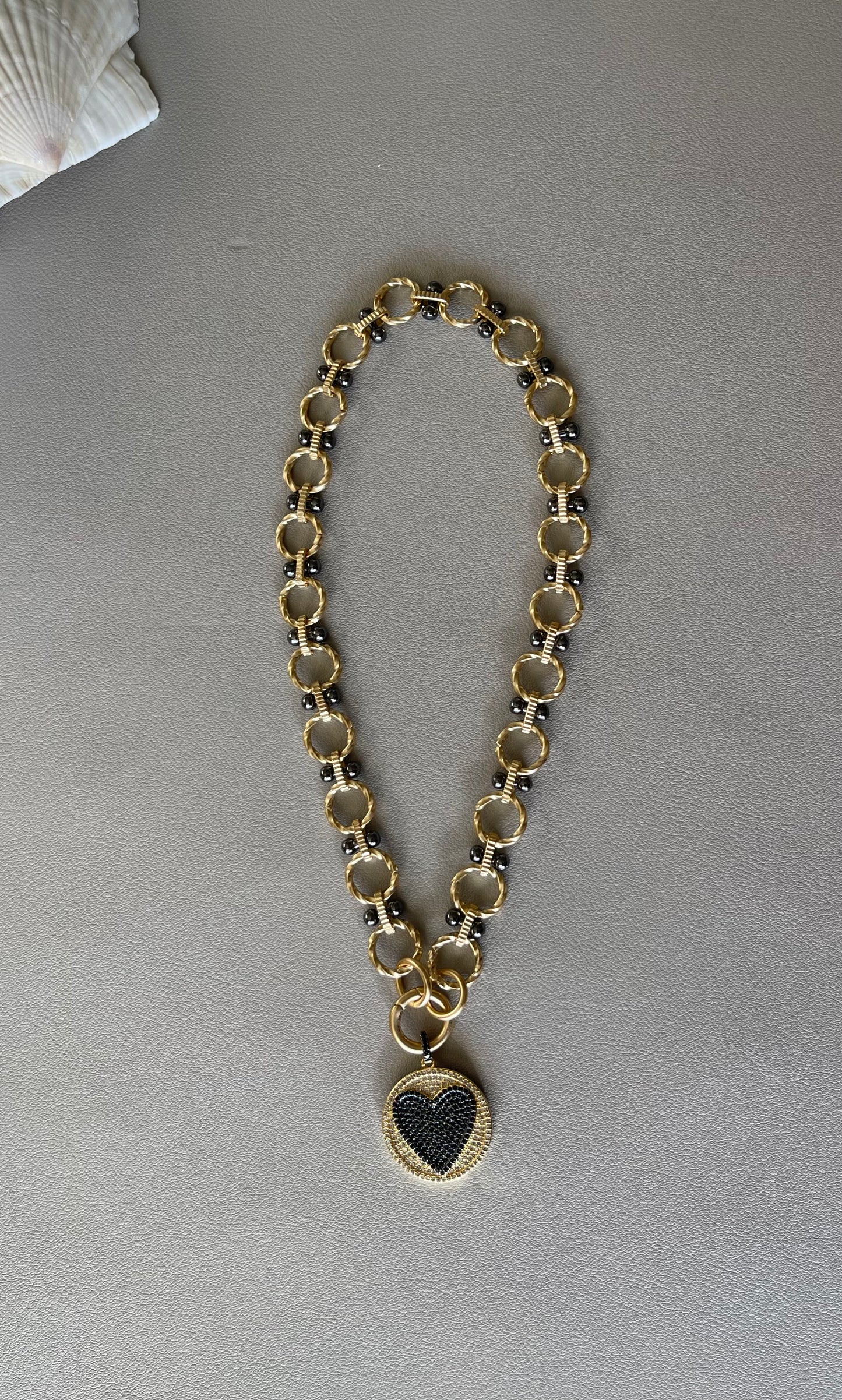 Heart On Your Sleeve Necklace: Brushed gold chain with gunmetal accents, a push gate circle clasp and pavé heart pendant