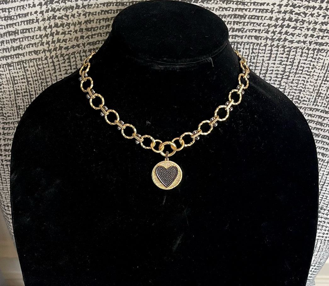 Heart On Your Sleeve Necklace: Brushed gold chain with gunmetal accents, a push gate circle clasp and pavé heart pendant